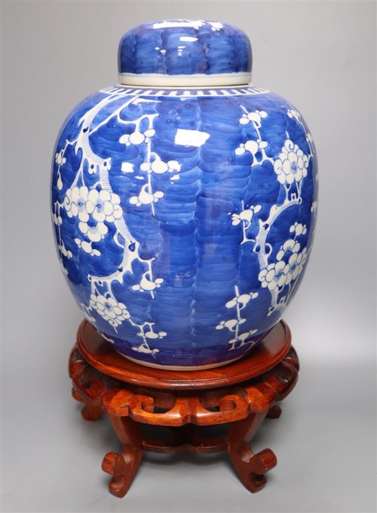 A pair of large Chinese blue and white prunus jars and covers, early 20th century, wood stands, 43cm total height